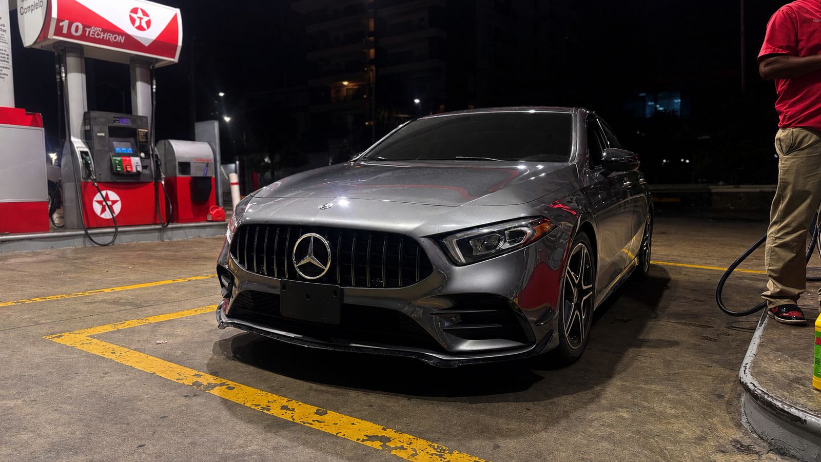 Mercedes-Benz gris repostando de noche en una gasolinera